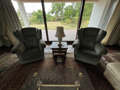 Vintage wing chairs with side tables and a table lamp