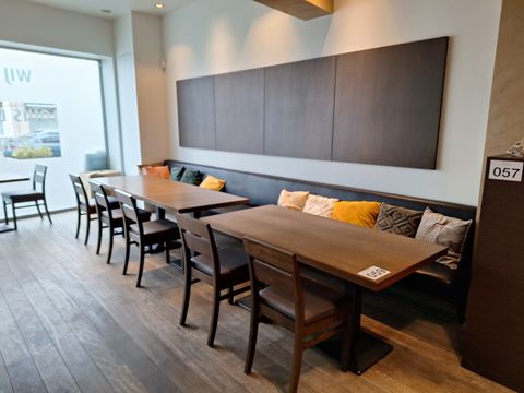 Installation de restauration élégante composée de canapés avec des coussins décoratifs, de tables en bois et de panneaux muraux d'ambiance.